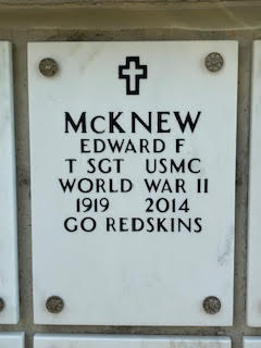 A white flat marble stone engraved with a cross and “McKnew Edward F T SGT USMC World War II 1919 2014 Go Redskins.”