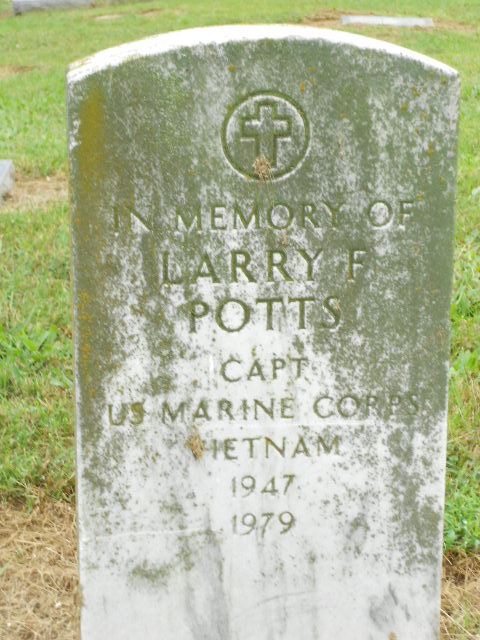 A colored white marble headstone engraved with, “In Memory of Larry F. Potts CAPT US Marine Corps Vietnam 1947-1979.”