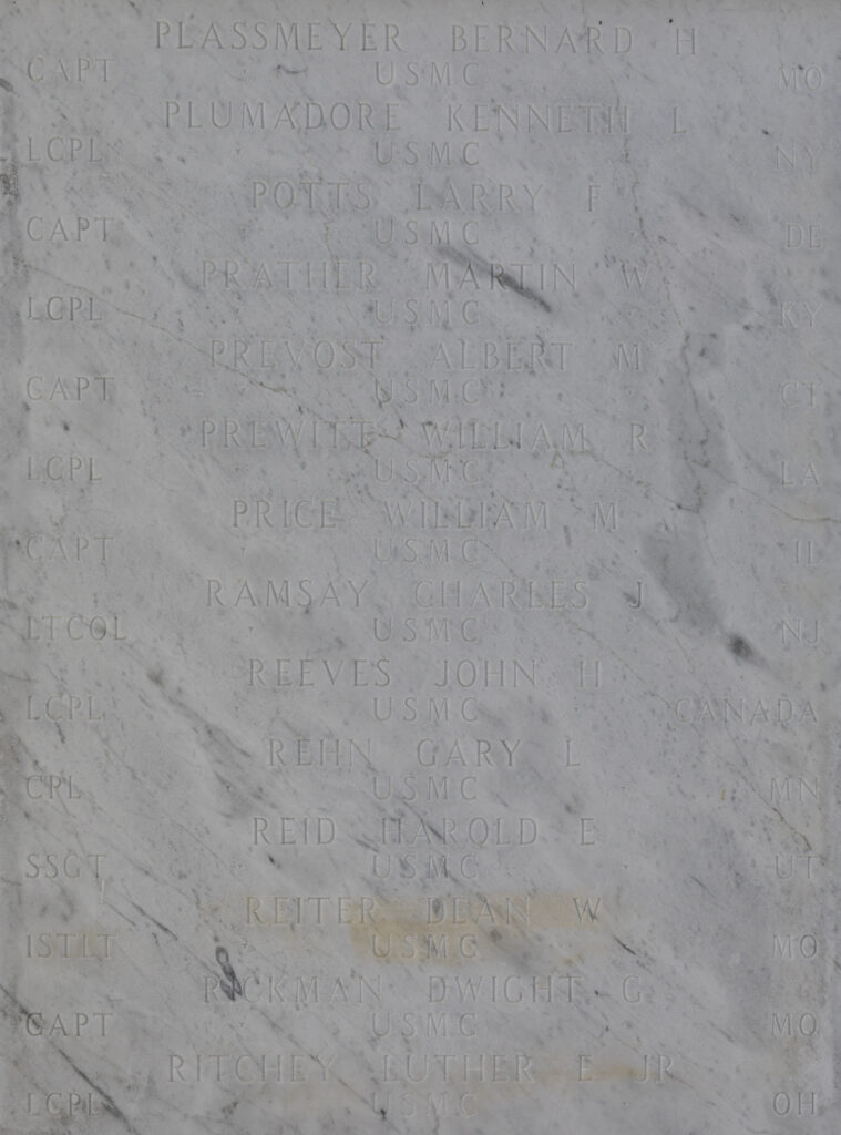 A white marble wall with multiple names engraved, including Larry Potts.