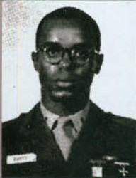 A black and white photo of a young Black man in uniform from the chest up.