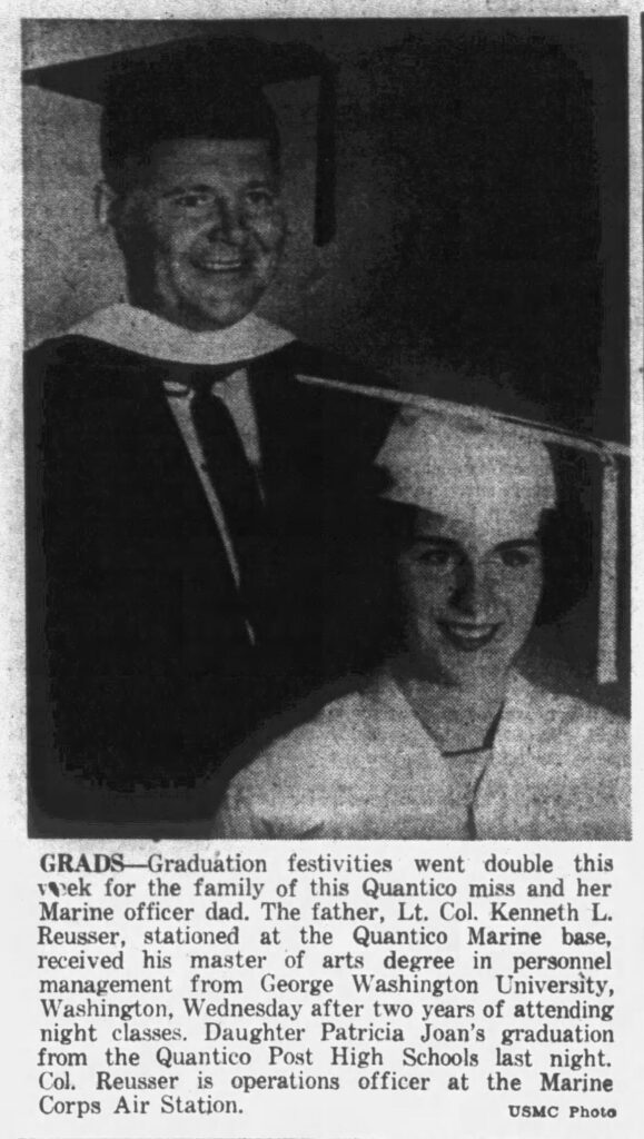 A black and white image of a man in a black graduation cap and gown standing behind a young woman in a white graduate cap and gown.