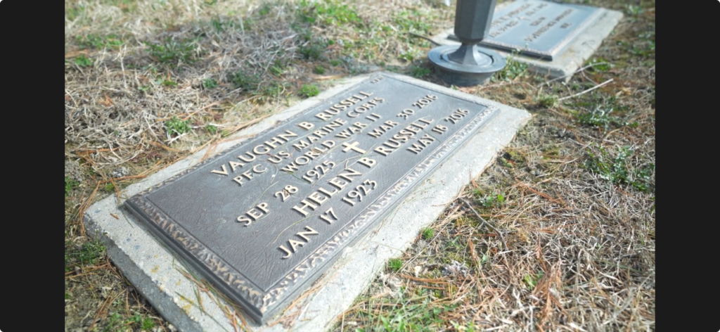 A color image of a bronze flat stone engraved with, “Vaughn B. Russell PFC US Marine Corps World War II Sep 28 1925 Mar 30 2016 Helen B Russell Jan 17 1923 May 18 2016.”