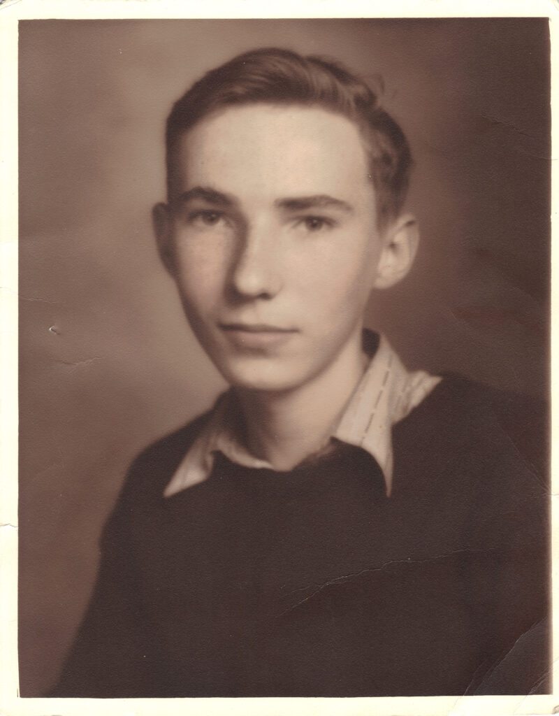 A black and white headshot photo of a younger White boy in a button-up shirt under a sweater.