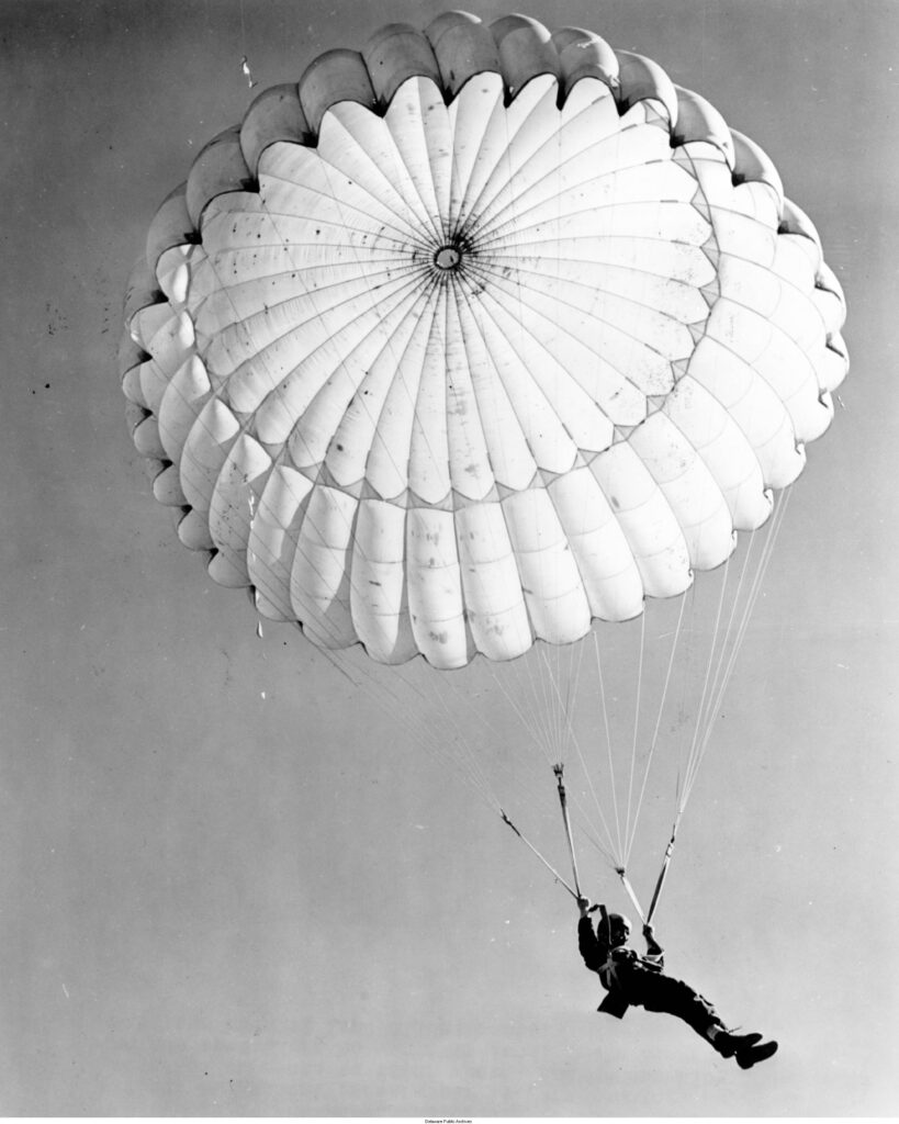 A black and white photo of someone parachuting in the air.