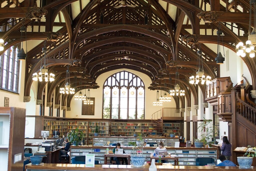 A color image of a library with an intricate wooden beam ceiling.