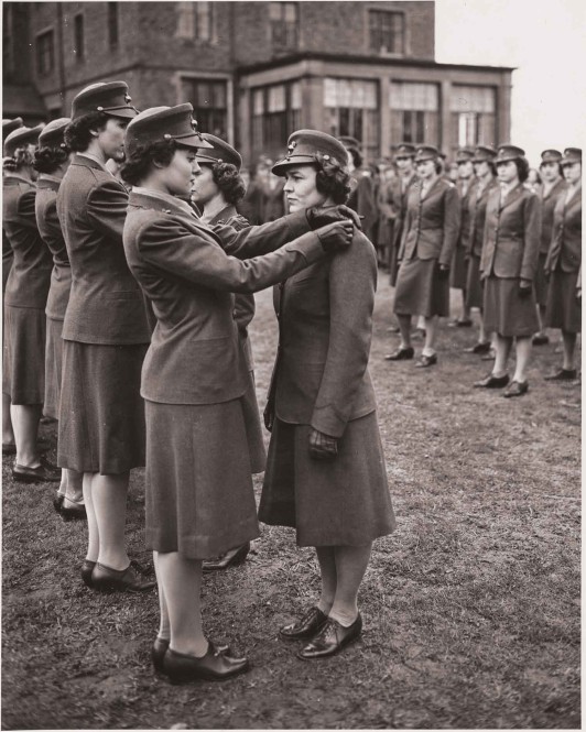 A black and white image of several women standing in formation outside in uniform.