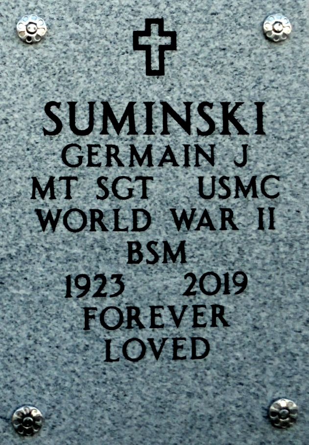 A gray marble slab engraved with a cross and “Suminski Germain J. MT SGT USMC WORLD WAR II BSM 1923 2019 Forever Loved”