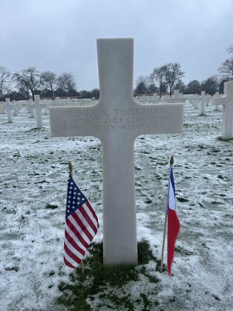 A white marble cross engraved with "James A. Timberman Capt 1271 Engr Combat BN New Jersey Mar 15 1943."