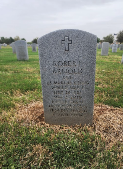 A color photo of a gray, arched headstone.