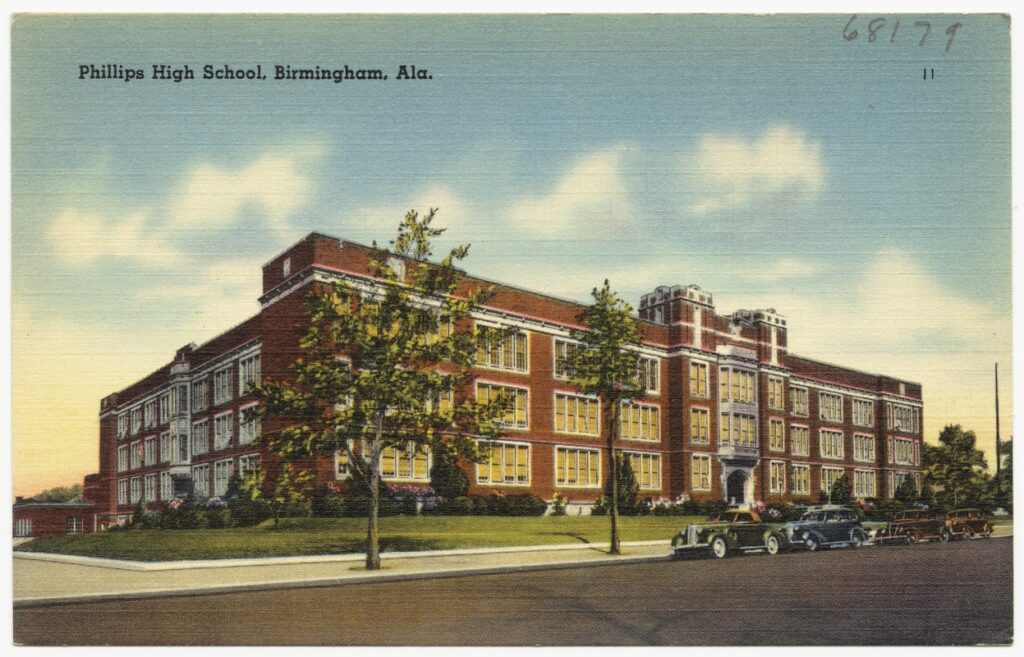 A color postcard showing a three-story brick school building from the front and corner. 
