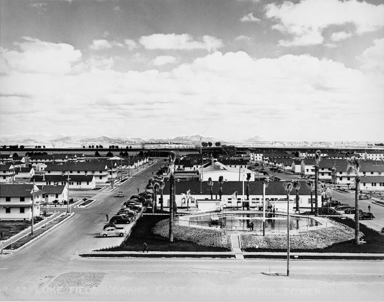 A black and white photo taken of multiple houses from elevation. There are mountains in the distance.