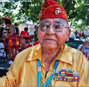 A color photograph of an elderly Navajo man in a military cap, yellow shirt, and military ribbons.