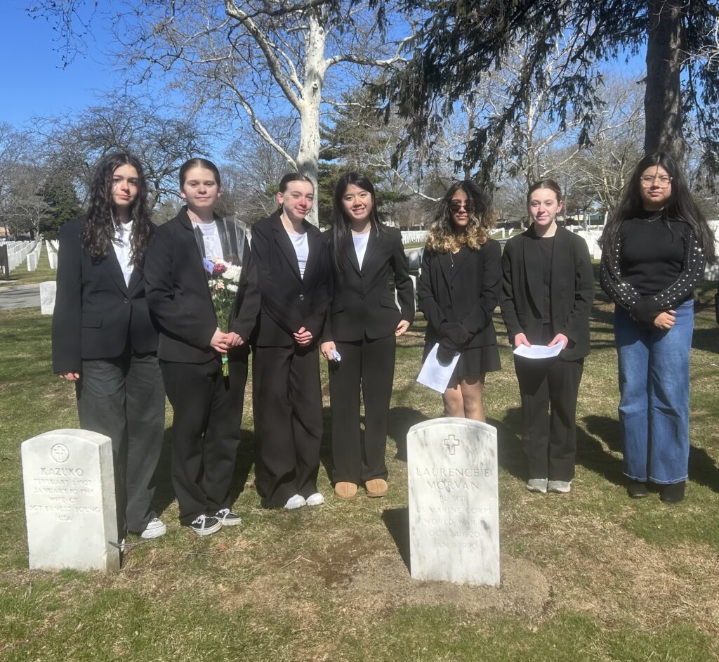 A color image of several students standing in a cemetery.