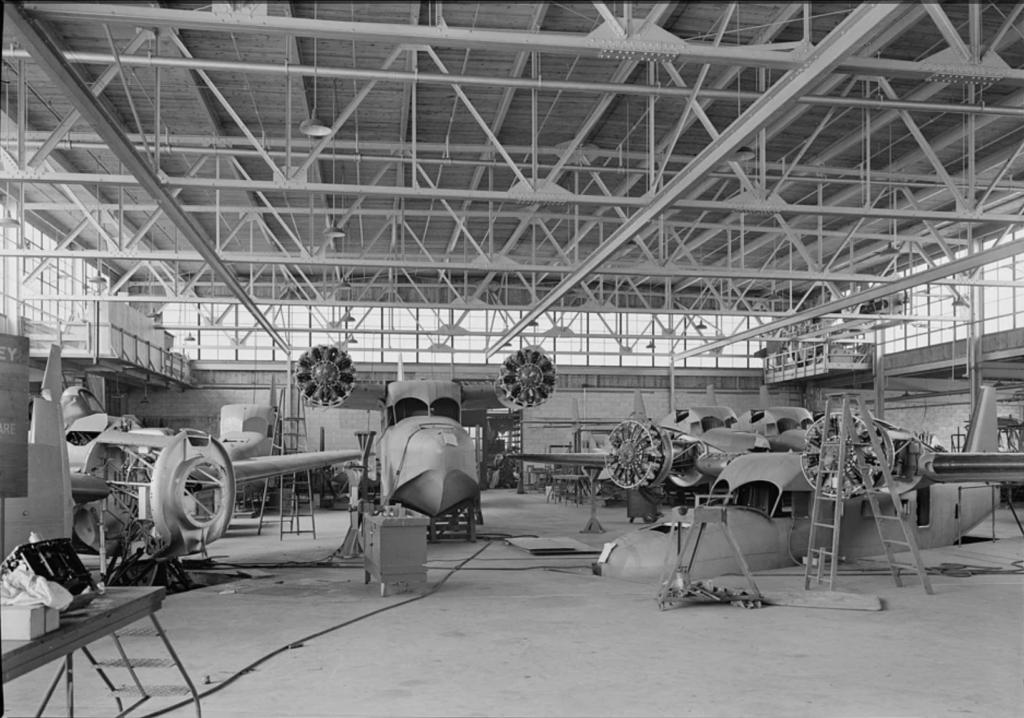 A black and white image of several aircraft being built in a factory.