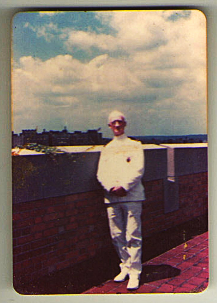 A color image of an older White man in uniform standing on a rooftop.