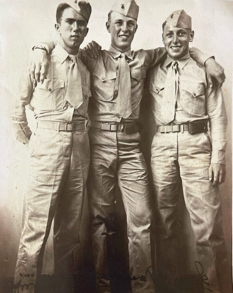 A black and white photograph of three young White men in uniform. 