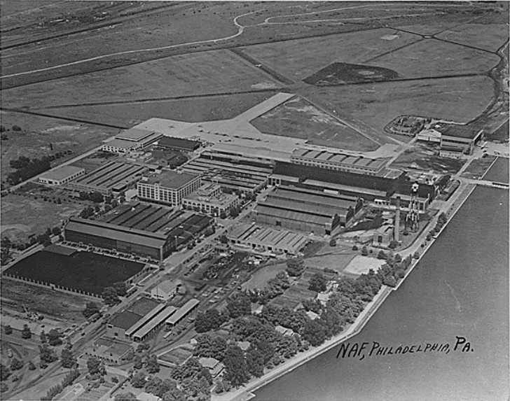 A black and white aerial image of several factory buildings on the water.