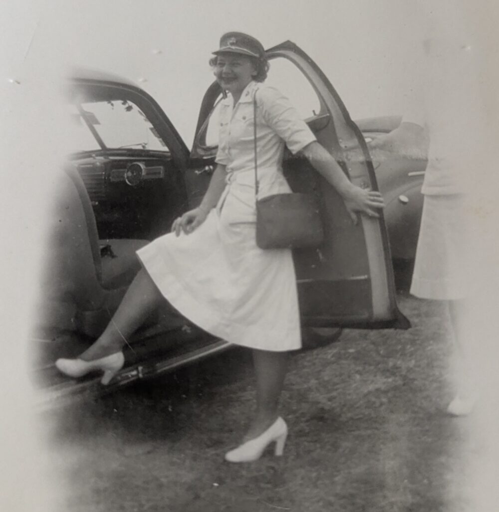 A black and white photo of a young White woman in a white dress uniform.