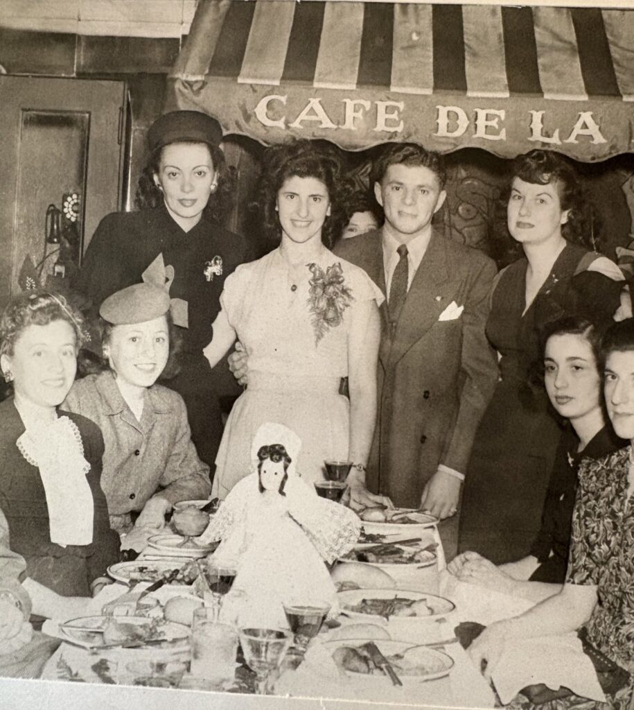 A black and white photo of several young people dressed up in a formal dining set-up.