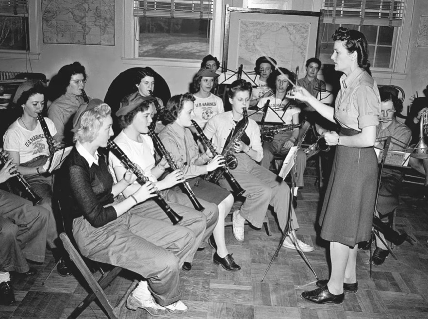 A black and white image of several women sitting playing instruments.