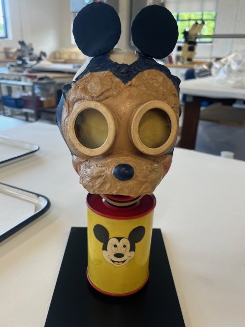 A color photo of a small gas mask shaped like a mouse face.