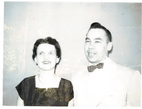 A black and white photo of a young couple in dress attire.