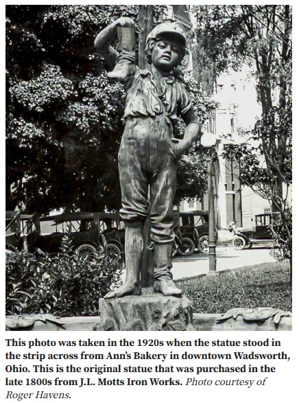 A black and white picture of a statue of a little boy carrying a boot.
